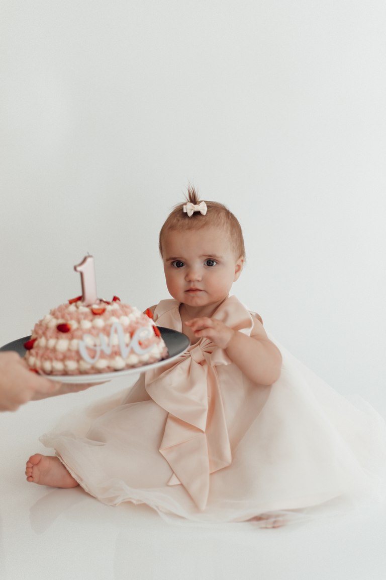 Baby mit Geburtstagstorte und einer Kerze zum ersten Geburtstag