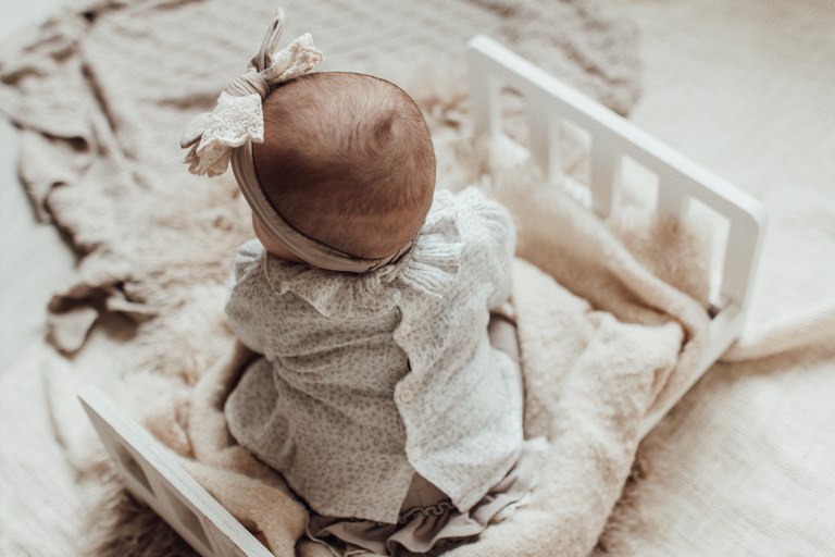Baby mit Schleife auf einer hellen Decke
