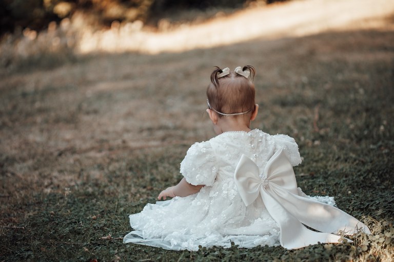 Kleinkind im weißen Kleid auf einer Wiese