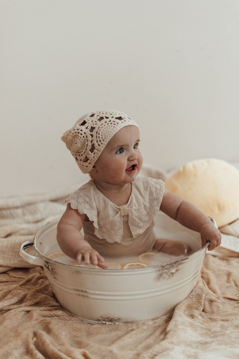 Baby schaut aus einer kleinen weißen Badewanne