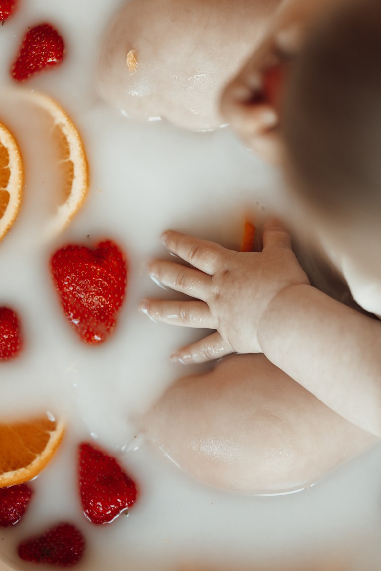 Kleine Hand und Erdbeeren im Milchbad