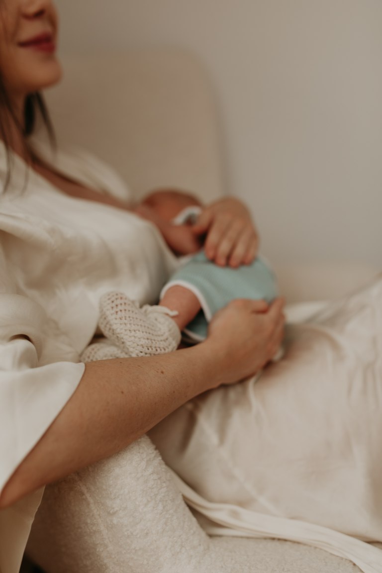 Neugeborenes liegt geborgen im Arm seiner Mutter