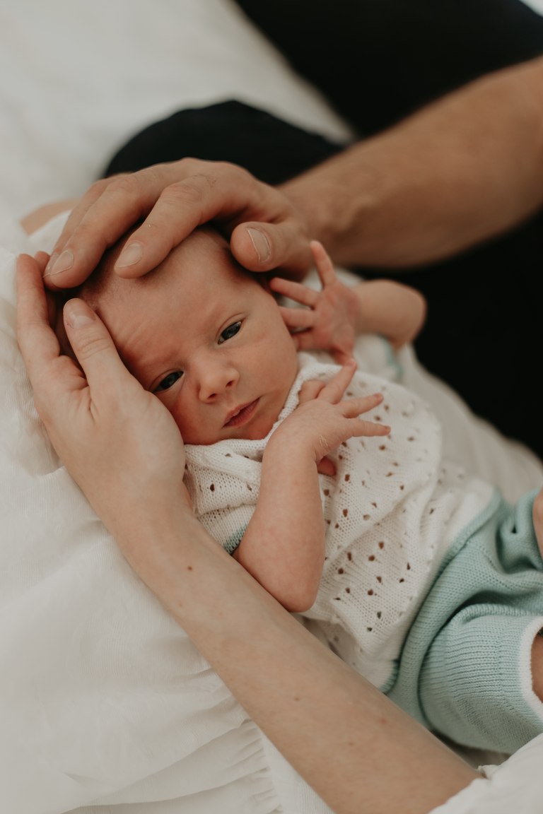 Elternhände streicheln sanft den Kopf ihres Babys