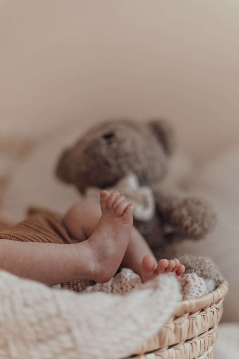 Babyfüße neben einem weichen Teddybären