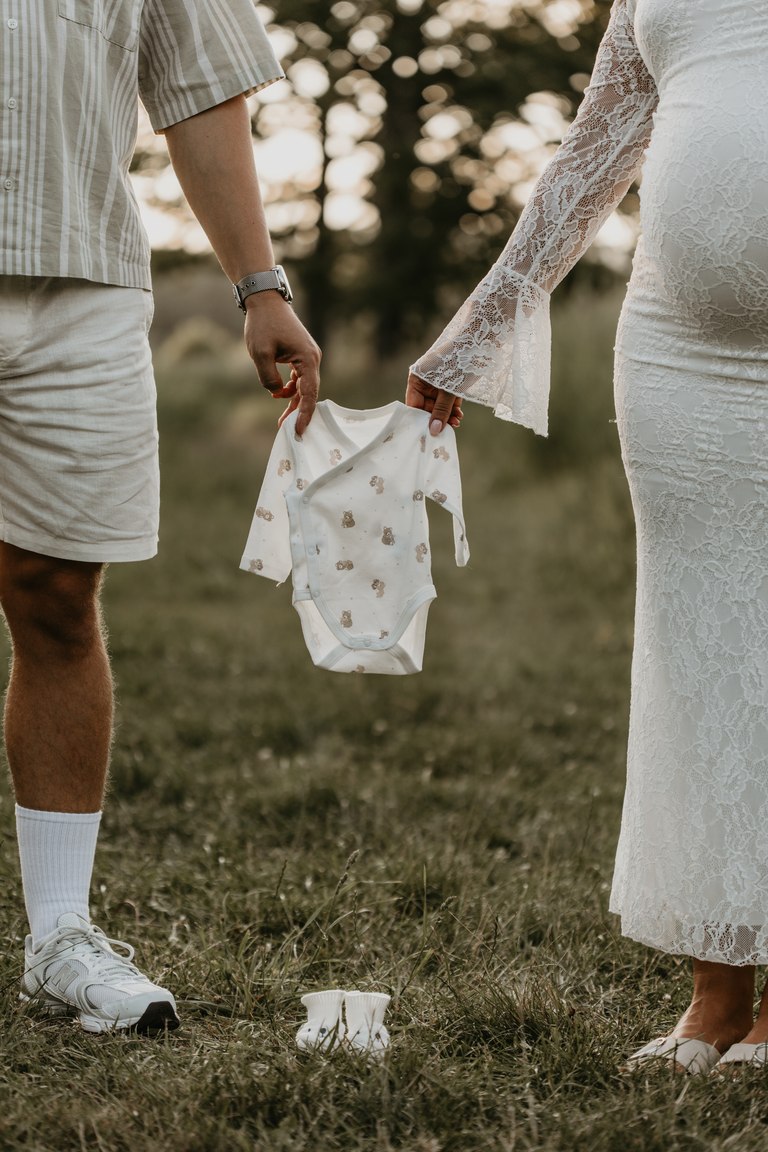 Ein Babybody zwischen den Händen werdender Eltern