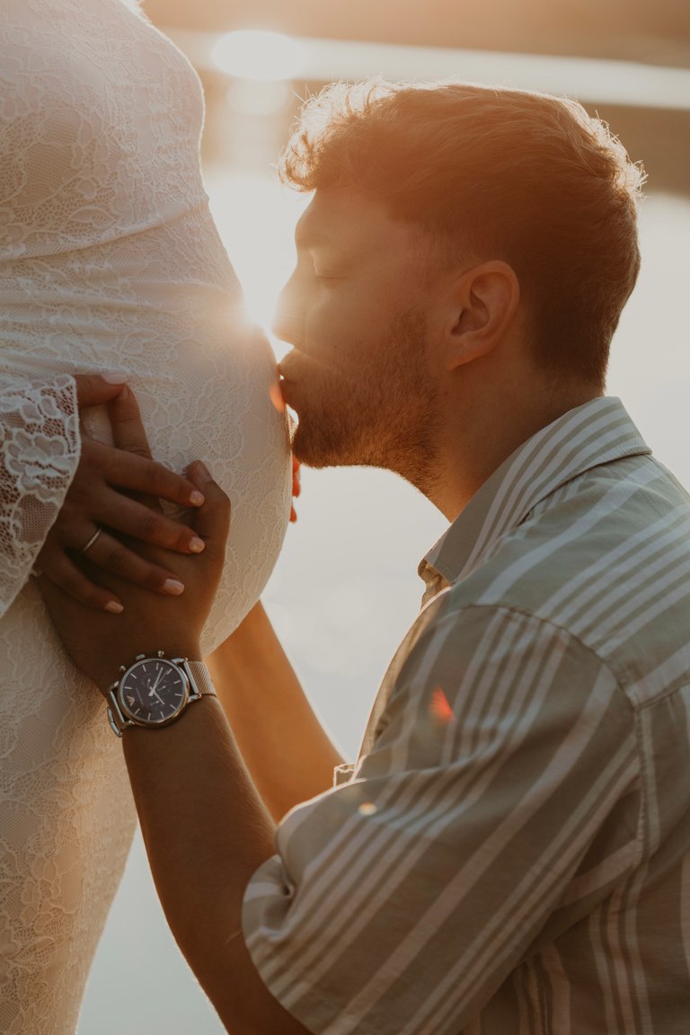 Ein werdender Vater küsst den Babybauch